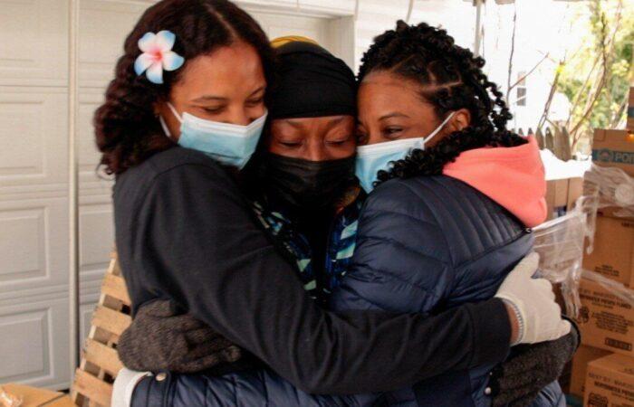 Jeannette, Tiffany, and Brittany hugging at a distribution event.